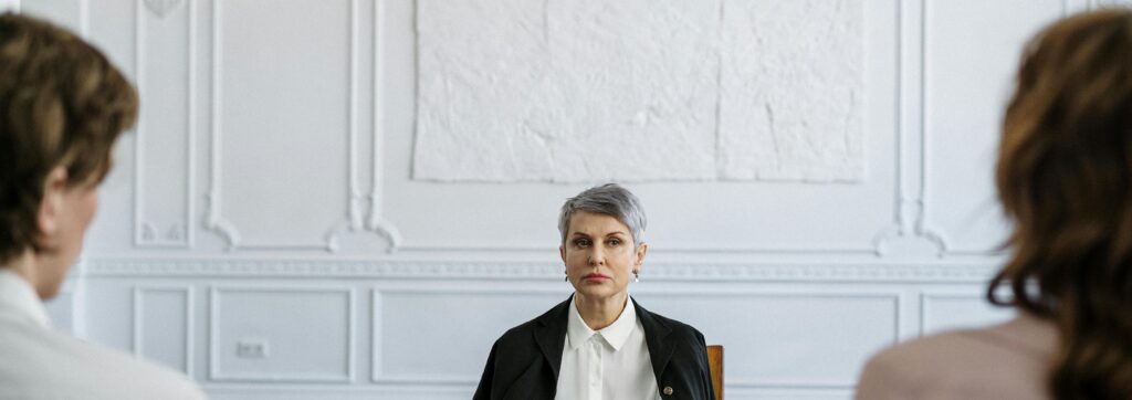 Mature woman sitting between two individuals in a serious discussion, symbolizing divorce mediation