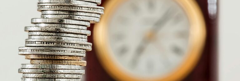 Stack of coins with a clock in the background, representing the importance of time in financial health and planning